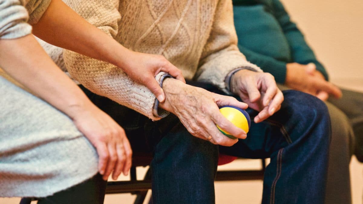 A carer's hands gently holding an older person's hands