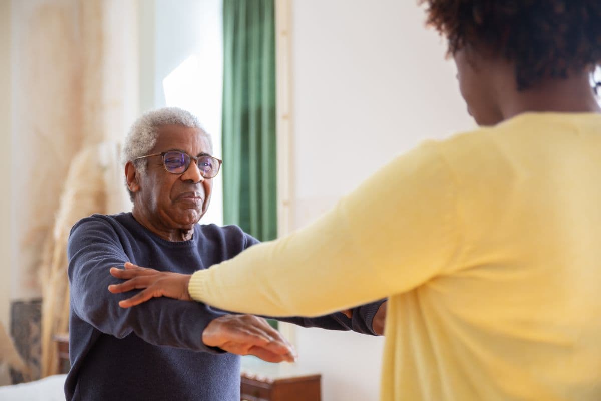 A support worker helping an older man with a task at home